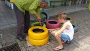 Perfurando os pneus para prender com os arames com a ajuda do Sr. Benê.